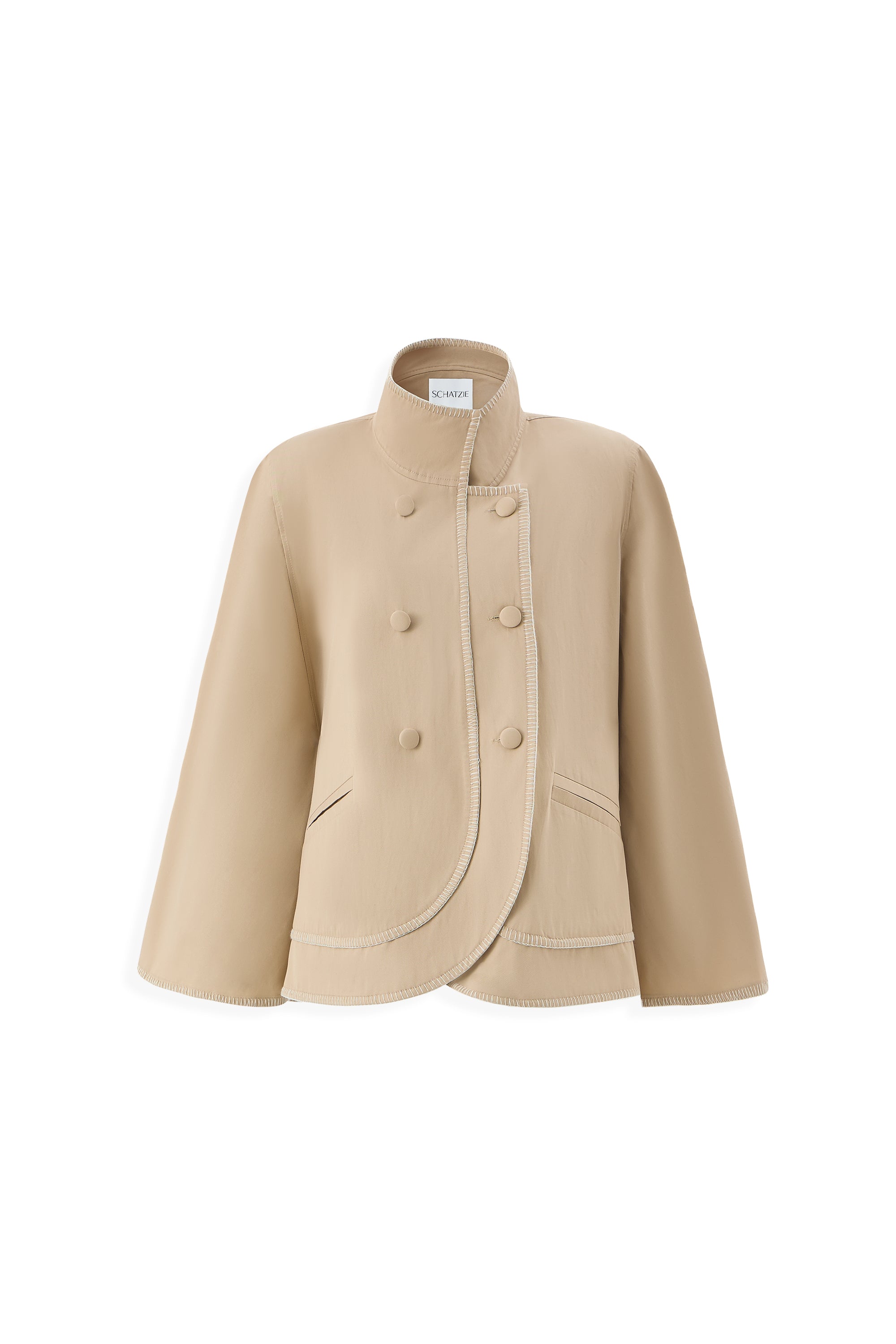 The SABLE CAPE is an ecru, double-breasted high-neck jacket featuring a minimal silhouette, asymmetrical curved front closure, decorative stitching, and two angled front pockets.